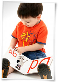 Toddler pointing at book and reading while sounding out each letter